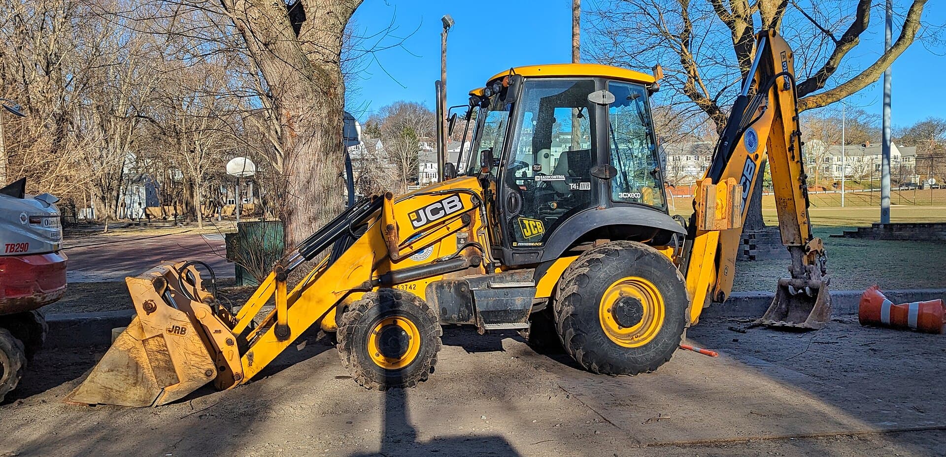 Backhoe loader with front bucket and rear excavator arm on a worksite