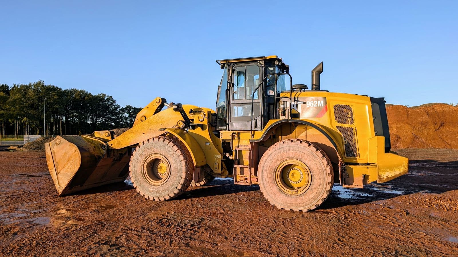 Yellow wheel loader with a full bucket on a mine and construction pad