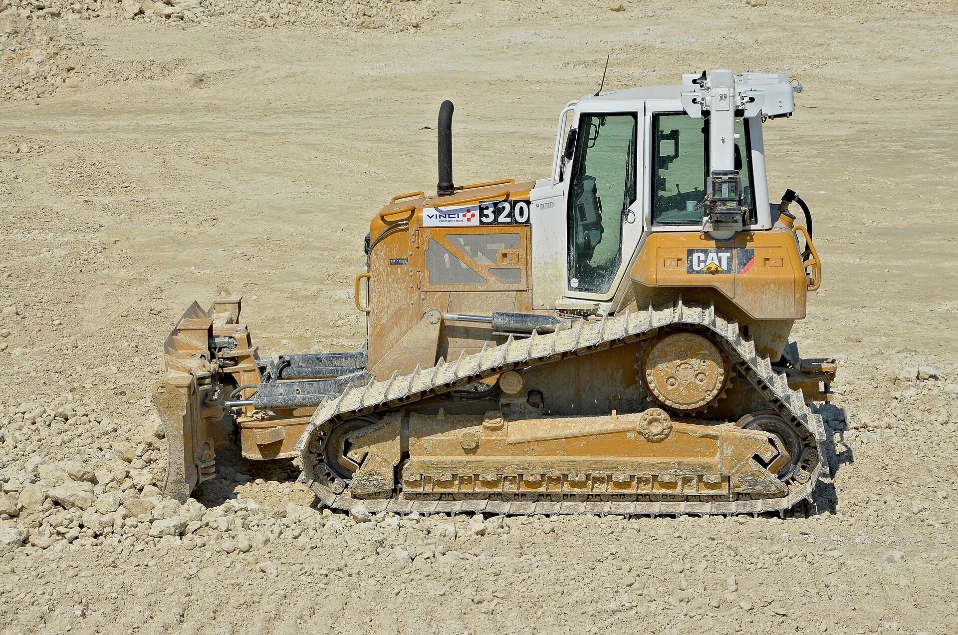 A bulldozer pushes and spreads material with its front blade during site preparation and road work.